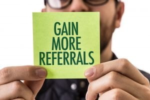 man holding post it note that says gain more referrals