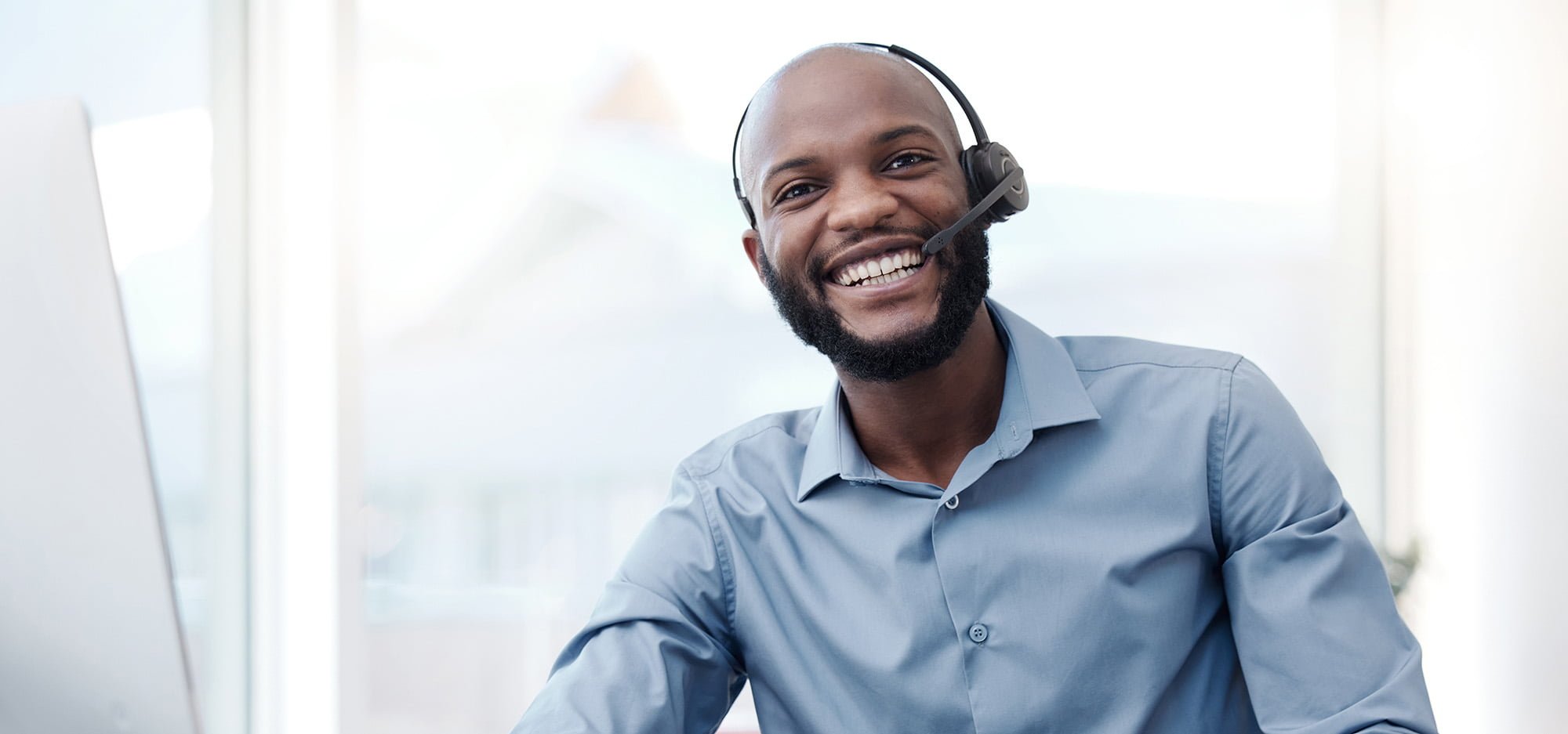 man smiling while using a headset at a desk