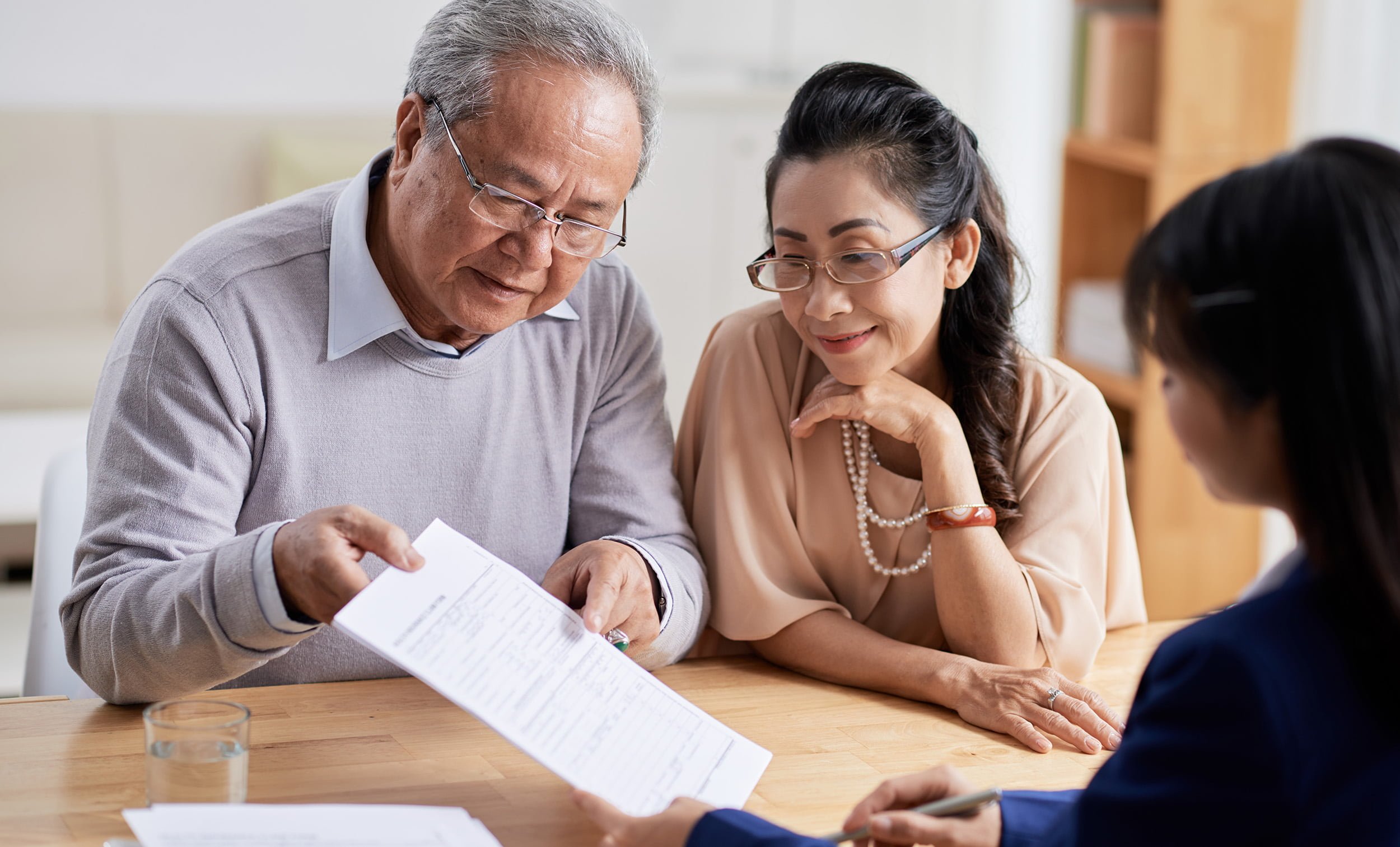 senior husband and wife studying terms of preneed insurance application while having meeting with preneed insurance agent